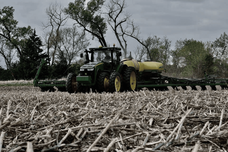 A tractor pulling a planter through corn stubble
